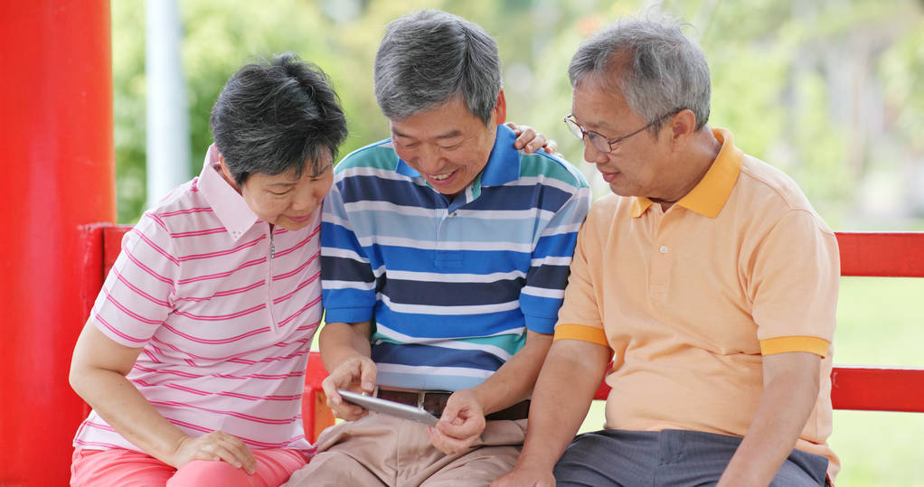 senior old friends using mobile phone to take photo at outdoor park