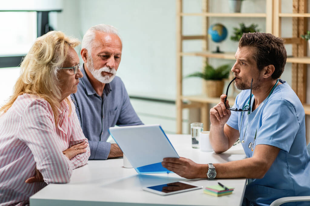 pensive doctor talking with senior couple about their medical reports at his office.