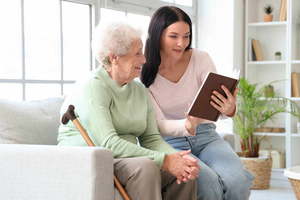 senior woman and her daughter with book at home