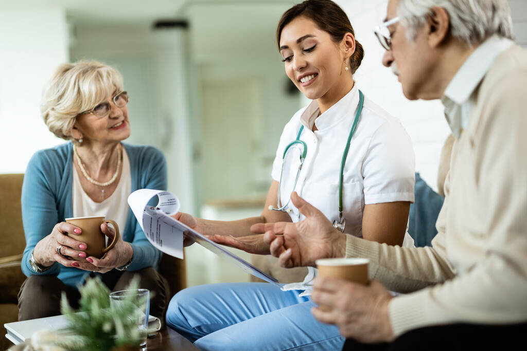 Healthcare professional reviewing care information with an older couple at home.